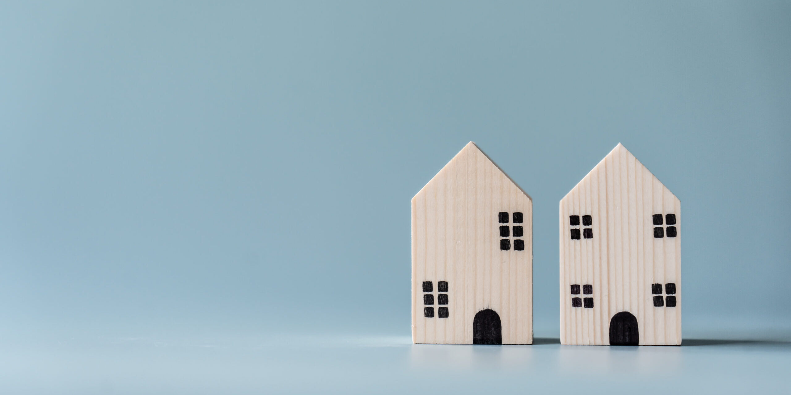 Small wooden house on light blue background for real estate and residential building concept