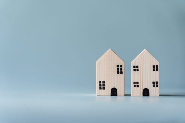 Small wooden house on light blue background for real estate and residential building concept